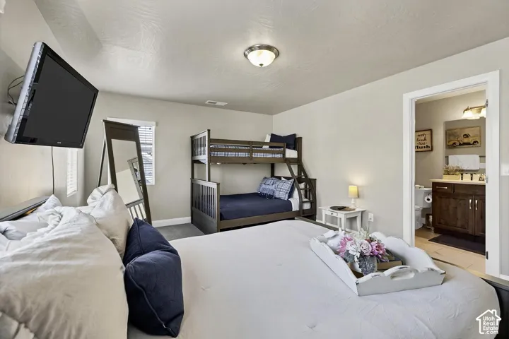 Neutral-toned room featuring wall-to-wall carpeting, flush-mount lighting, and attached bathroom with dark wood-finish cabinetry