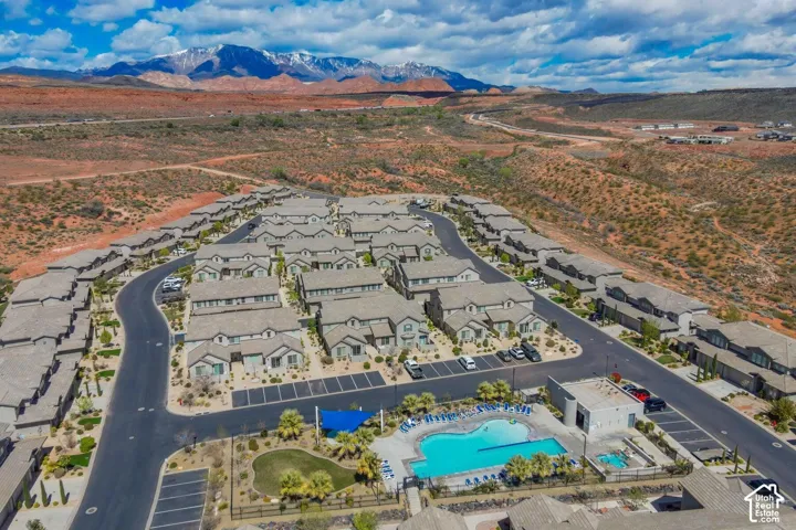 Aerial perspective of residential community featuring a swimming pool, spa, manicured lawn areas, and mountain backdrop