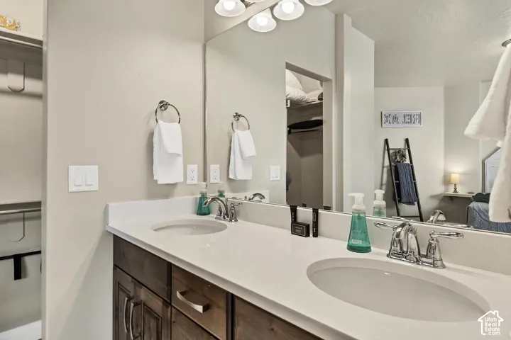 Dual-sink vanity with a solid-surface countertop, under-mount basins, polished chrome fixtures, and a wall-to-wall mirror