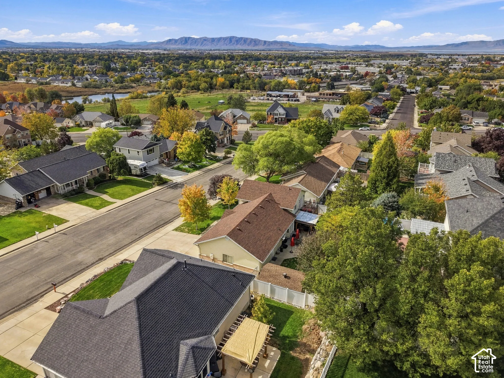 Aerial perspective featuring mountain backdrops, established tree-lined streets, concrete driveways, residential rooflines, and open space surroundings