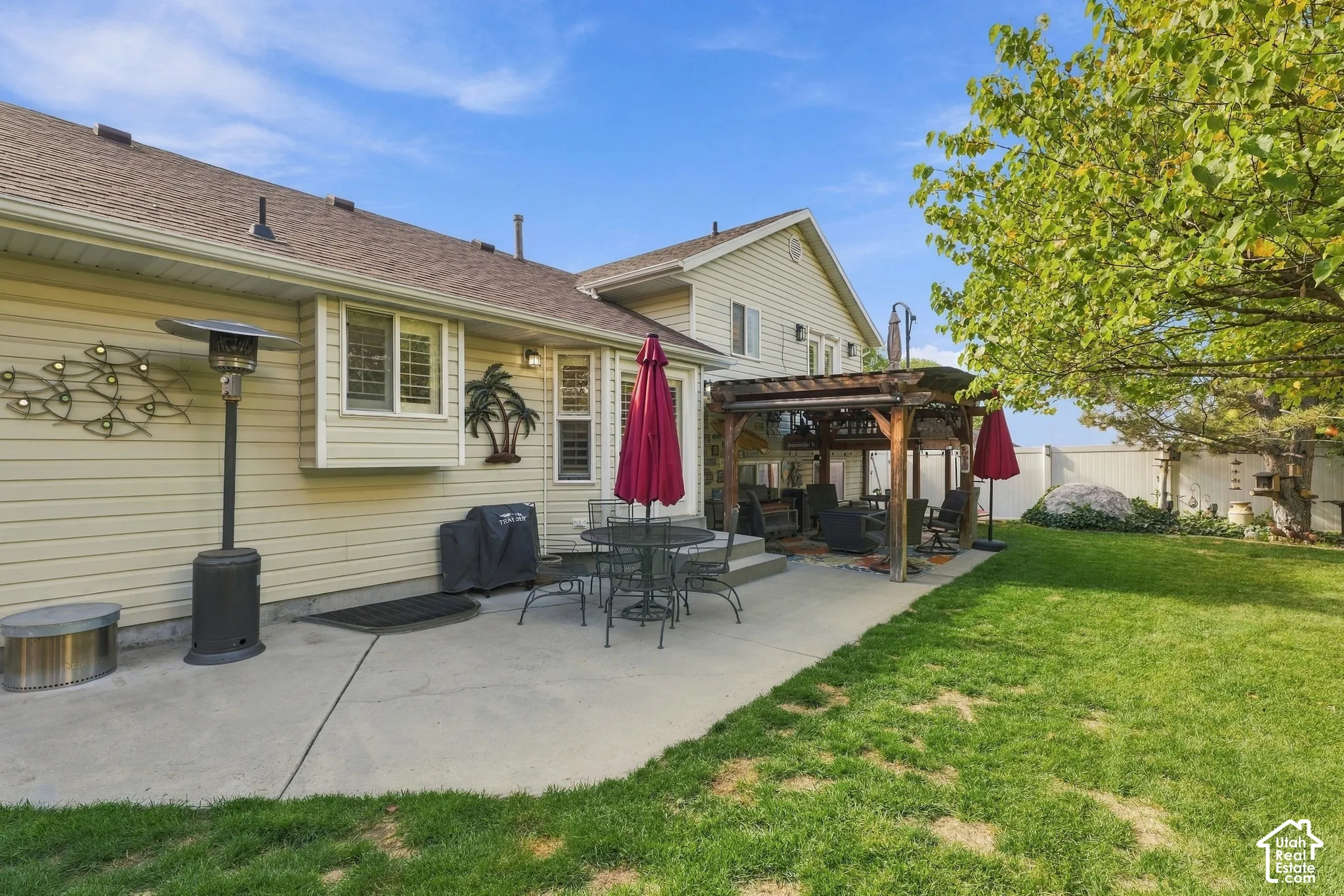Rear exterior featuring horizontal lap siding, a concrete patio, a covered wooden pergola, and a grassy lawn