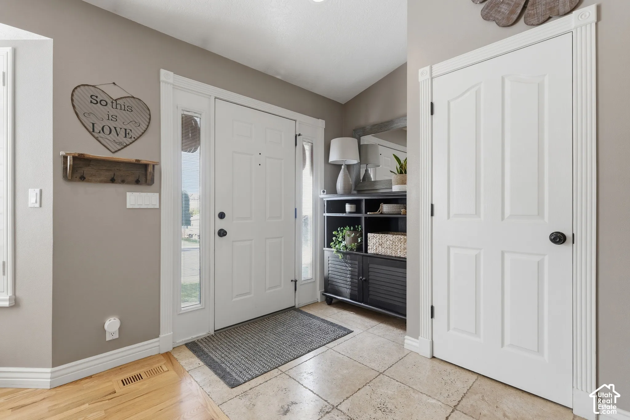 Entryway featuring a solid door with dual side lights, neutral wall tones, tile flooring, and interior doors with decorative millwork trim