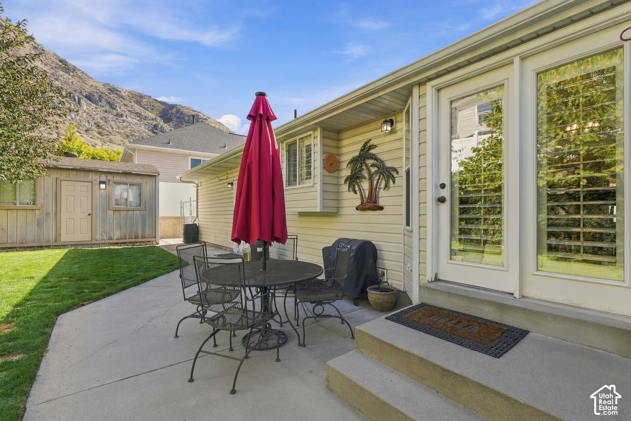 Exterior backyard space featuring a concrete patio, a detached storage shed, horizontal siding, and mountainous backdrop