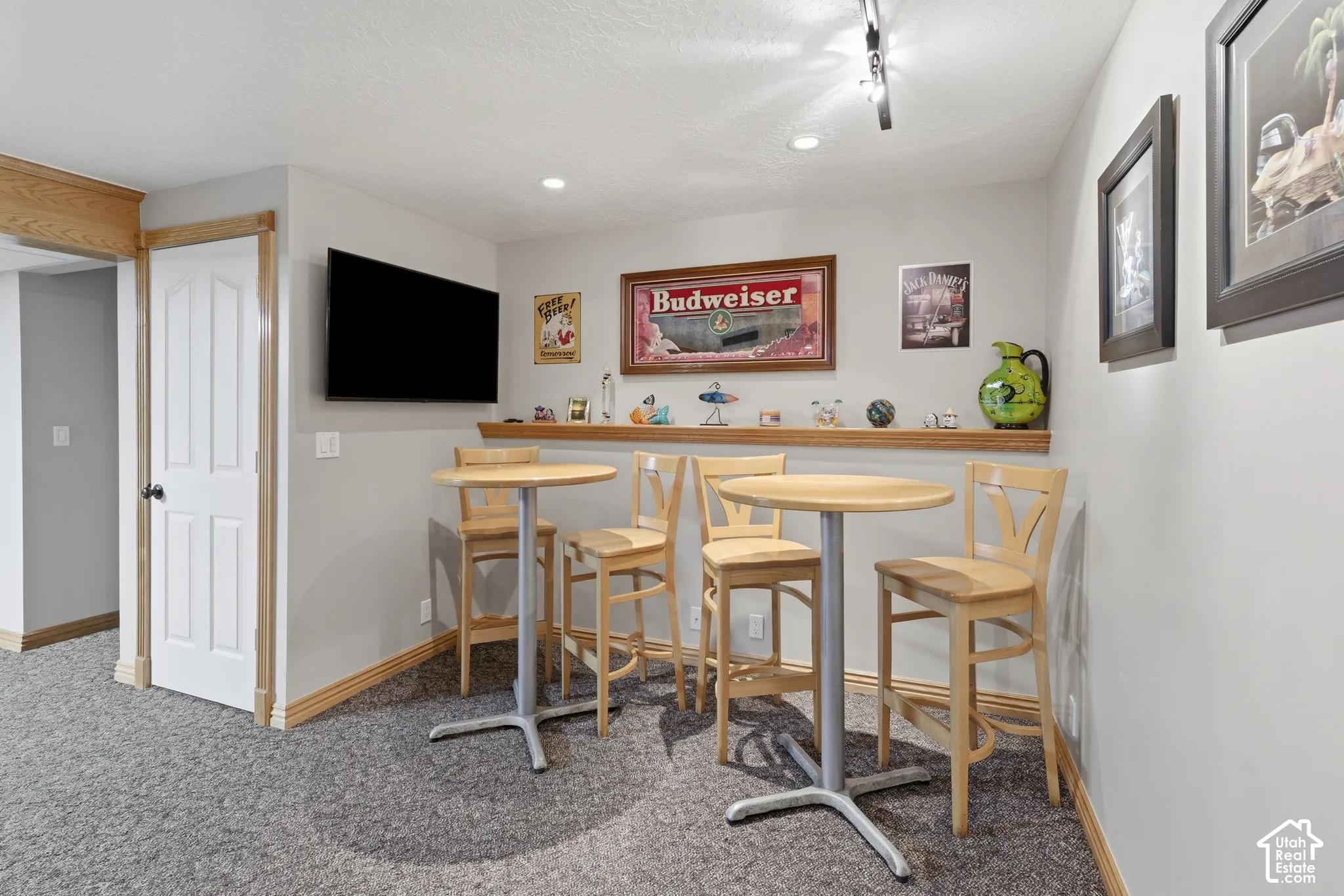 Built-in wooden display ledge, neutral wall-to-wall carpeting, four-panel interior door, and adjustable track lighting