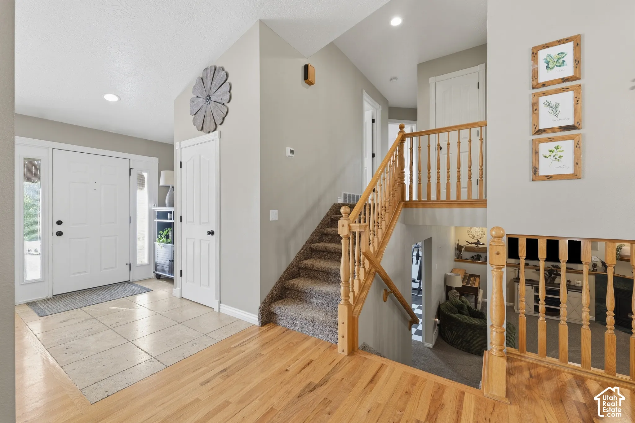 Entryway featuring neutral-toned walls, tile flooring, wood-finish flooring, vaulted ceilings with recessed lighting, and a wood staircase railing