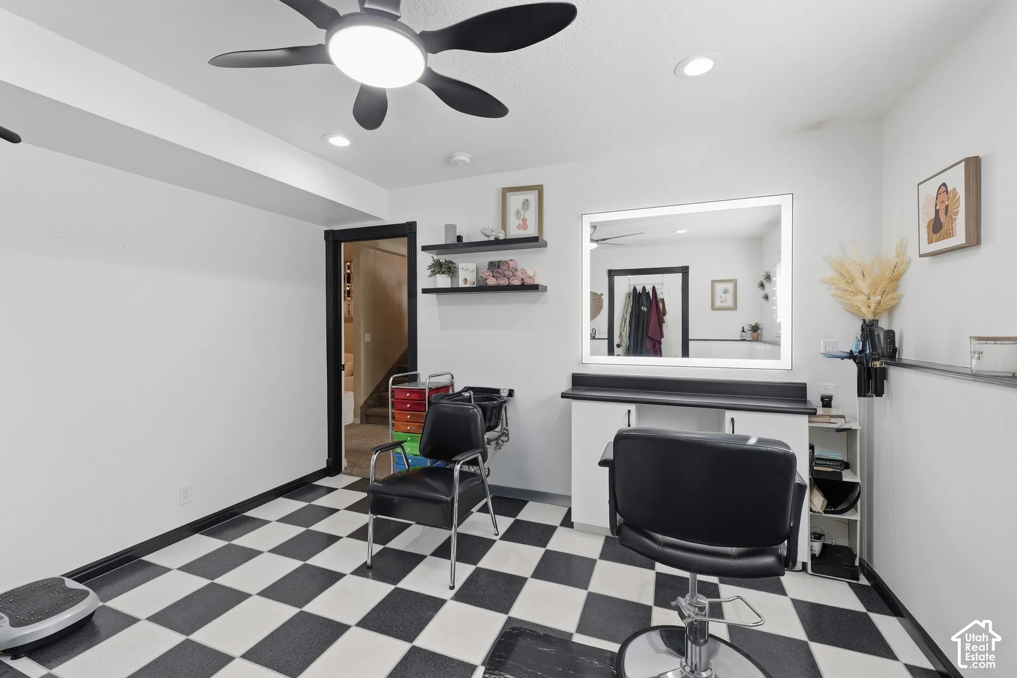 Checkerboard flooring, built-in vanity with a solid-surface countertop, LED-backlit mirror, recessed ceiling lighting, and black-finish floating shelving