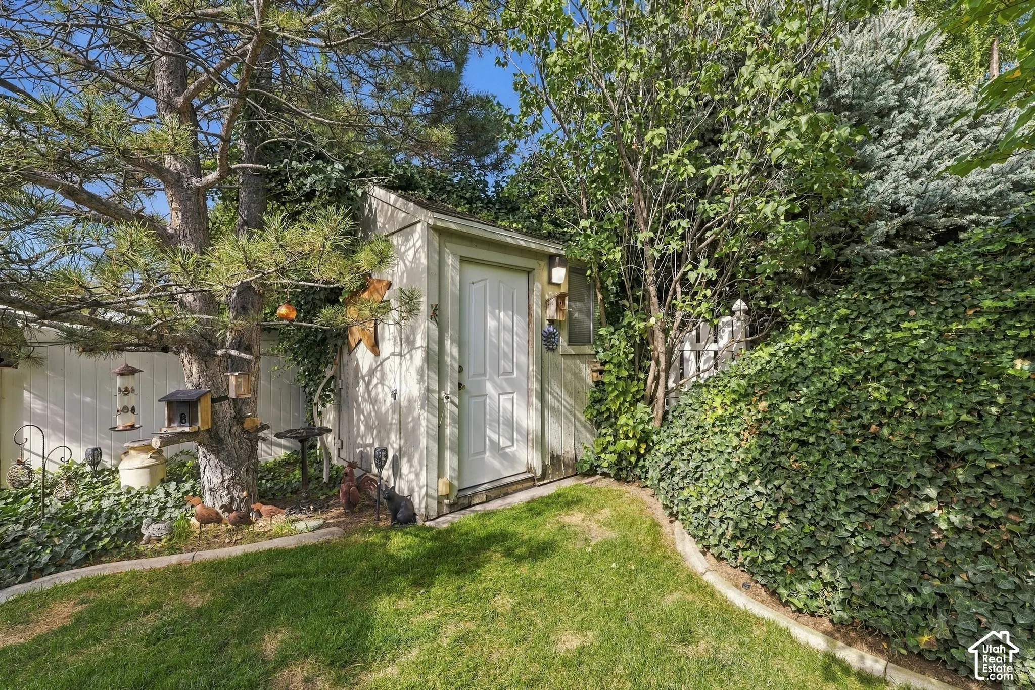 Exterior storage shed featuring vertical siding, a single-entry door, and concrete edging along a manicured lawn