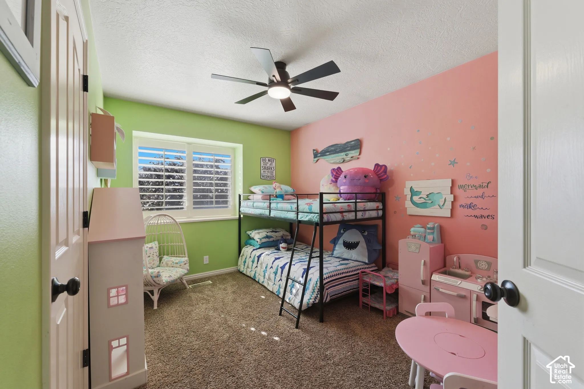 Bedroom featuring wall-to-wall carpeting, a multi-blade ceiling fan with integrated lighting, and white plantation shutters
