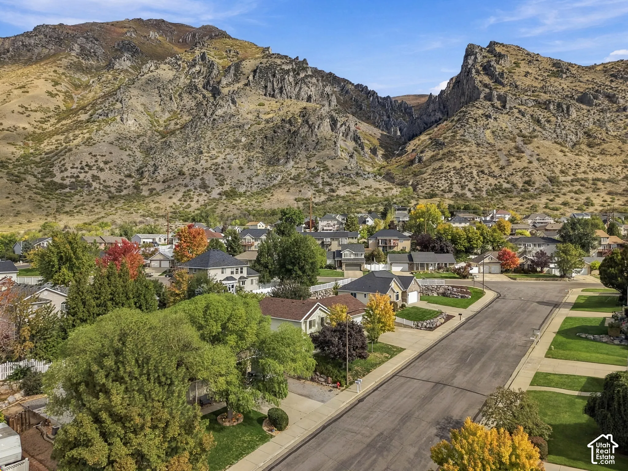 Aerial perspective featuring mountain terrain, asphalt streets, and mature deciduous trees