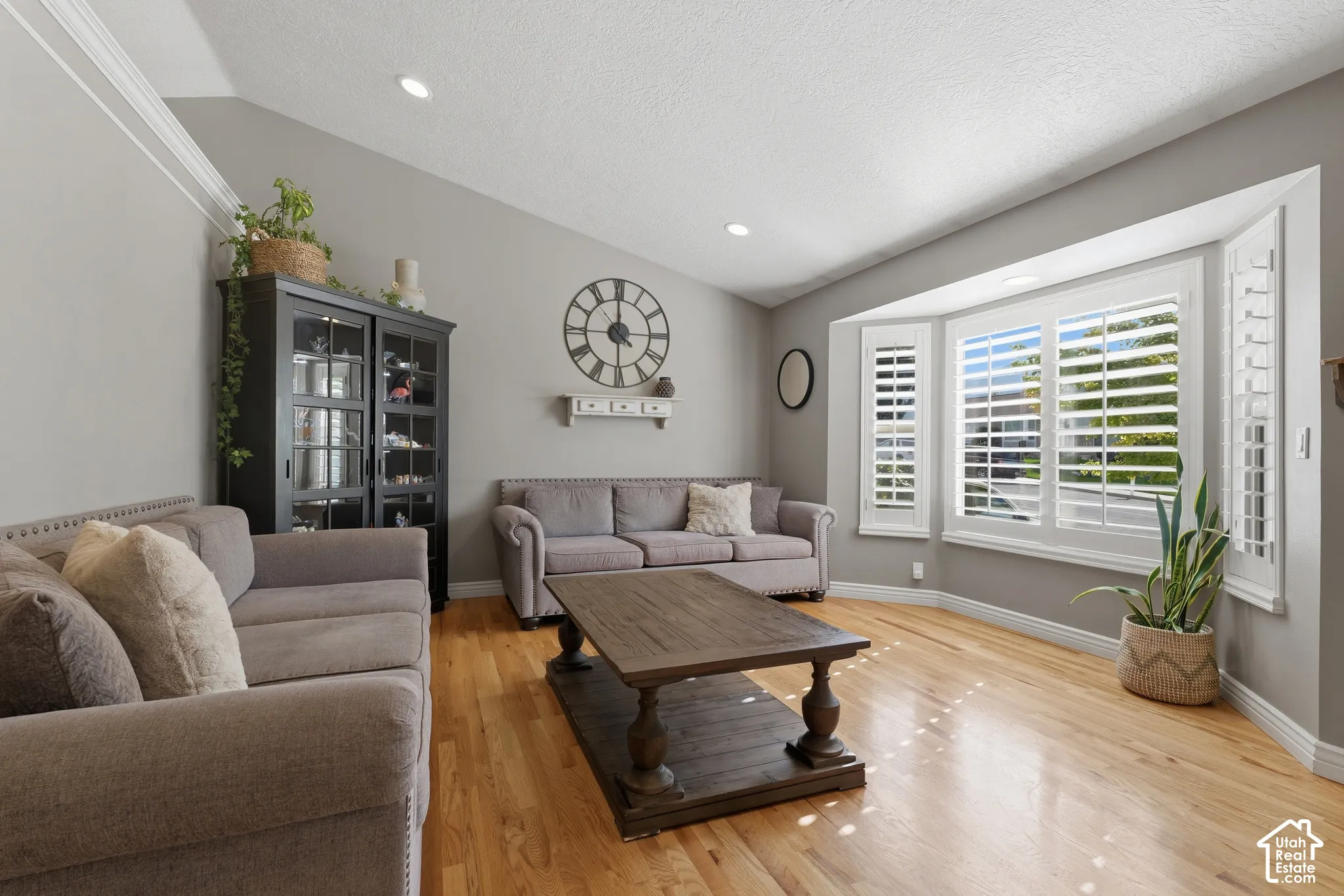 Vaulted ceilings, wood-finish flooring, bay window with plantation shutters, and recessed lighting