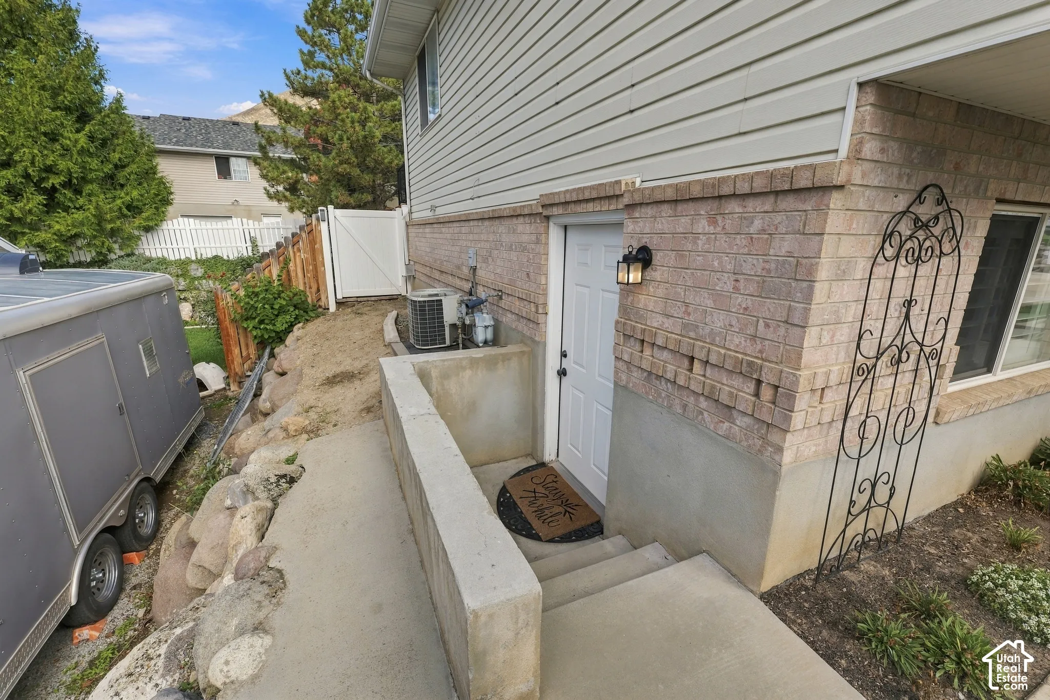 Exterior entrance featuring a concrete stairwell, brick masonry siding, horizontal vinyl siding, and an attached wall-mounted lantern fixture