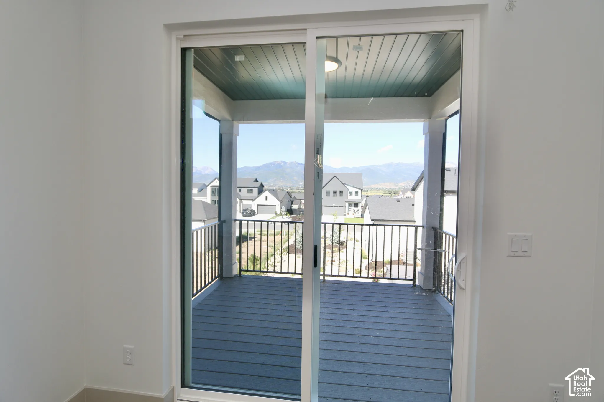Sliding glass door opening to a covered balcony featuring mountain scenery, metal railings, and wood-finish decking