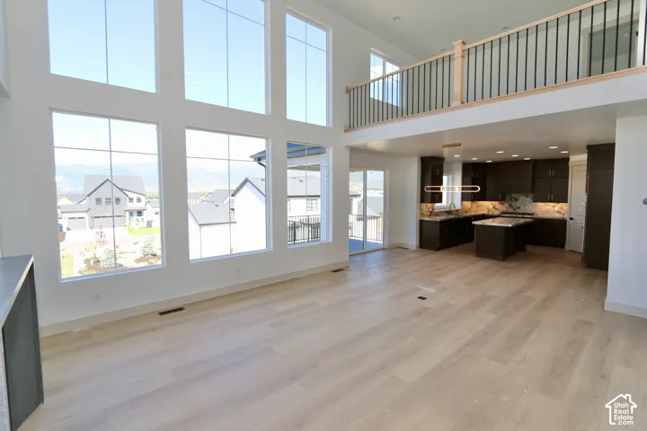 Expansive floor-to-ceiling windows, wood-finish flooring, custom dark cabinetry with a center island, and a mezzanine featuring a metal railing