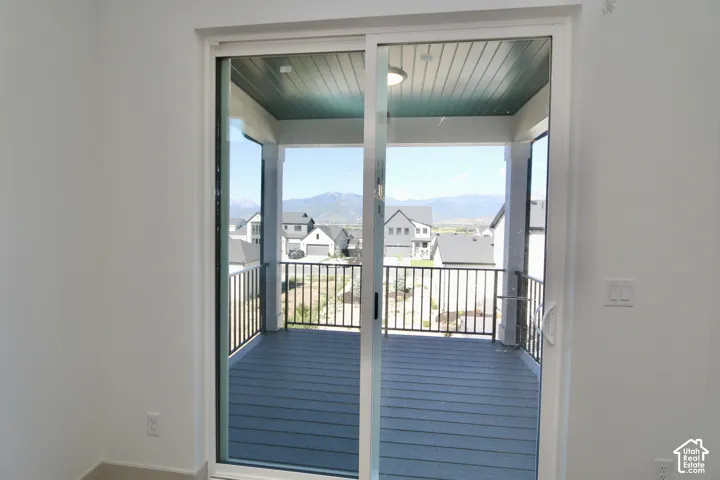 Sliding glass door opening to a covered balcony featuring mountain scenery, metal railings, and wood-finish decking
