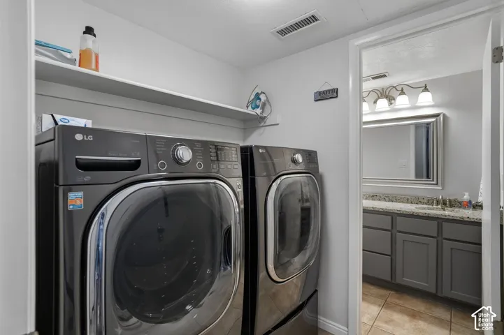 Laundry area featuring built-in shelving, tile flooring, and metallic-finish front-loading appliances