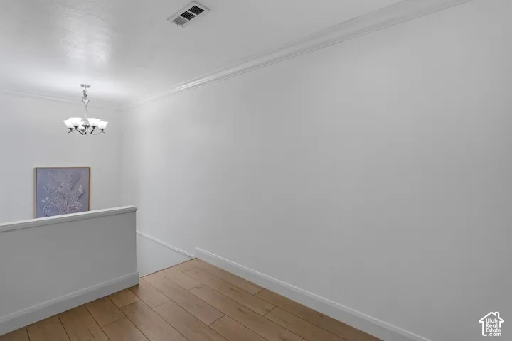 Wood-finish flooring, crown molding, and a multi-light chandelier