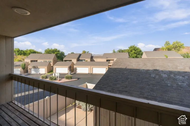 Covered balcony featuring wood-plank flooring, recessed lighting, and a metal railing
