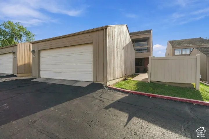 Exterior featuring vertical wood siding, attached garage, concrete driveway, and solid vinyl privacy fencing