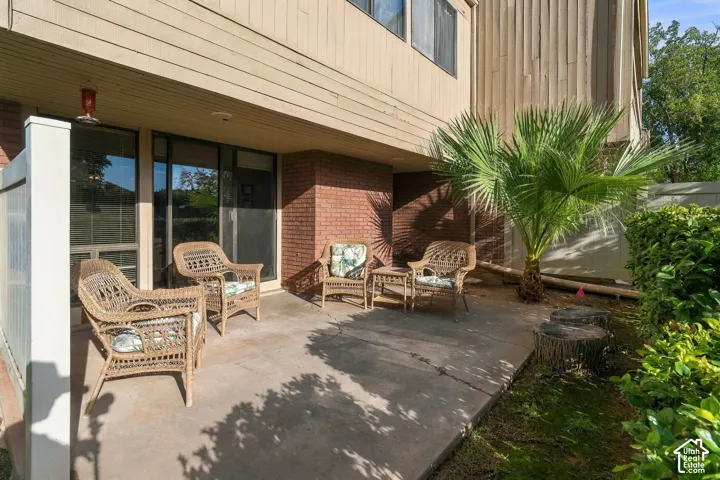 Concrete patio featuring a brick accent wall, wood-finish siding, and integrated sliding glass doors