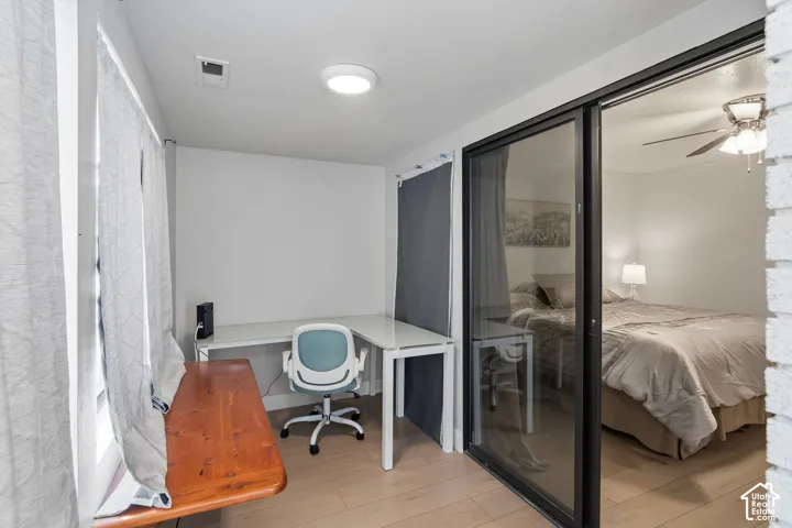 Wood-finish flooring, sliding glass door with a dark frame, and white wall surfaces