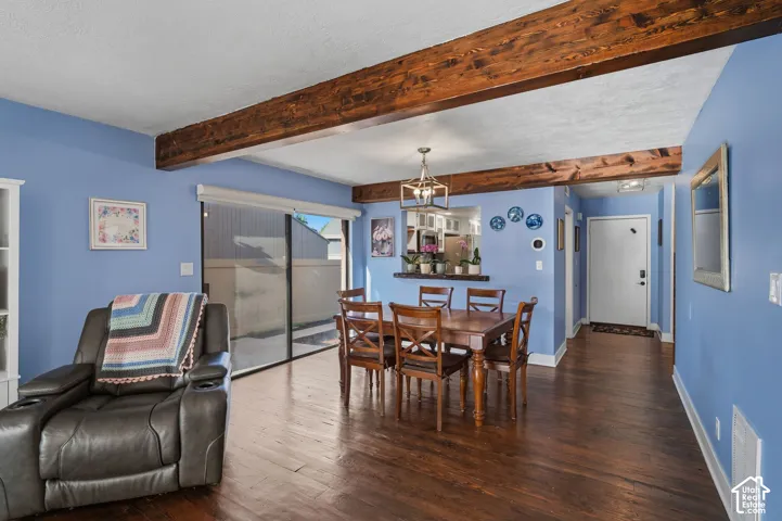Exposed stained-wood ceiling beams, wood-finish flooring, sliding glass door, and a built-in pass-through window with a counter ledge