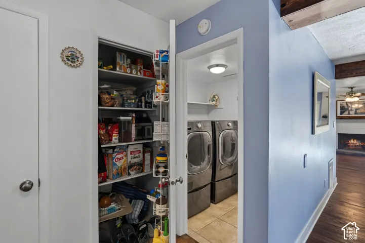 Storage pantry featuring built-in wire shelving and door-mounted storage racks, with an attached laundry area containing tile flooring and ceiling-mounted lighting