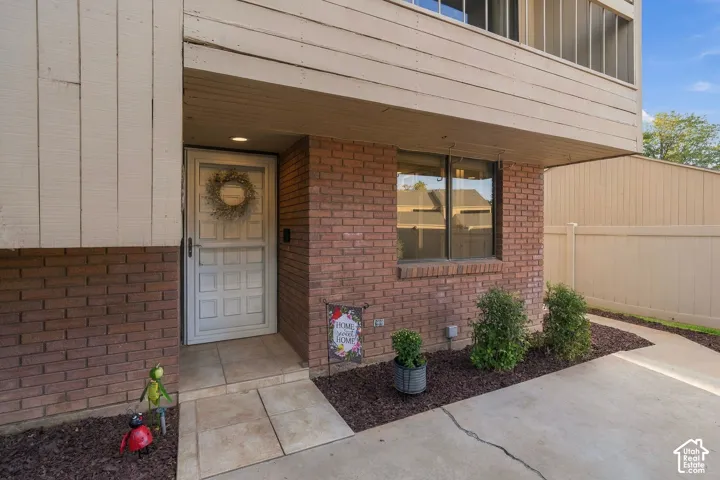 Exterior featuring brick masonry, vertical wood-finish siding, a paneled entry door, and stone tile flooring at the recessed porch entrance