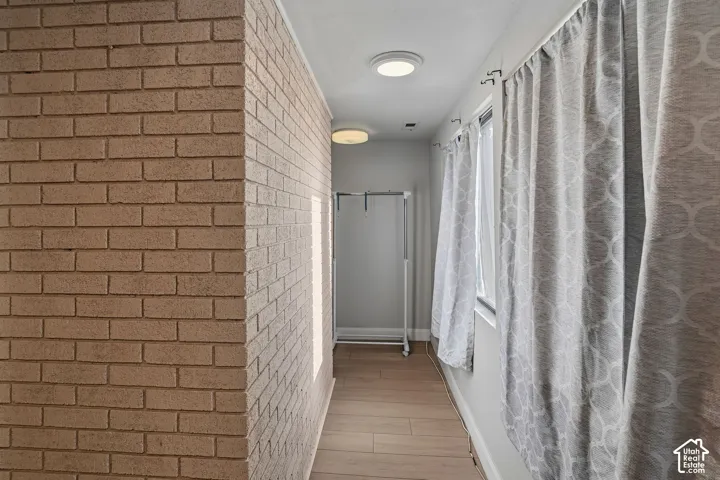 Interior space featuring a textured brick accent wall, wood-finish flooring, and recessed ceiling lighting