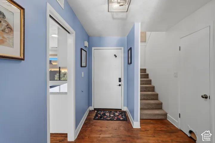 Entryway featuring wood-finish flooring, a flush-mount light fixture, and carpeted stairs
