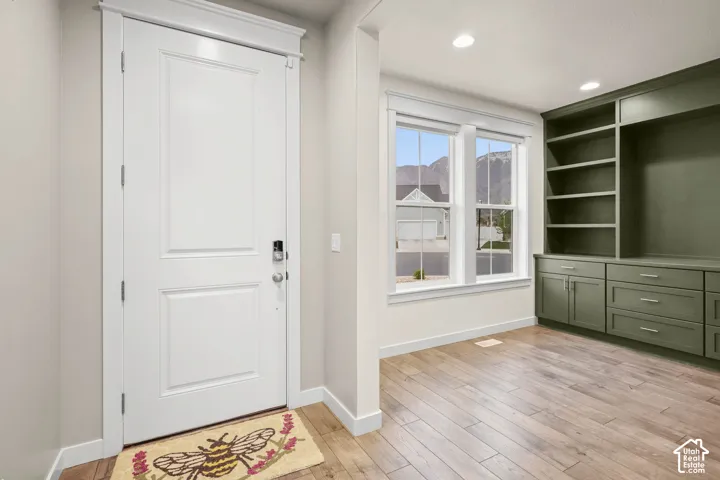Entryway featuring wood-finish flooring, custom built-in cabinetry with open shelving and drawers, double-pane windows, and recessed lighting