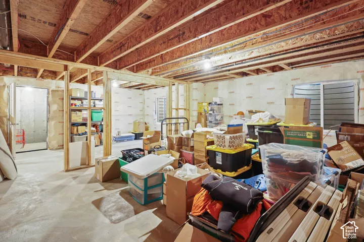 Unfinished lower level featuring exposed wood joist ceilings, concrete flooring, insulated perimeter walls, and an egress window