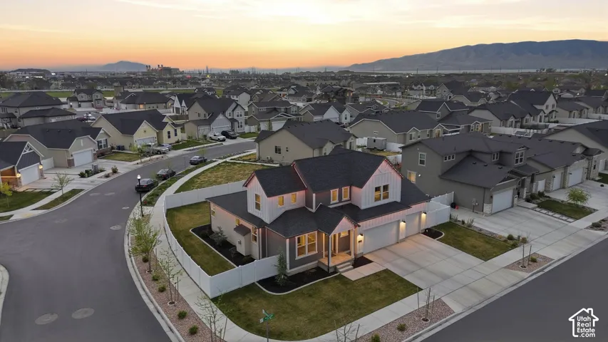 Two-story residence featuring a multi-gabled roofline, vertical siding accents, an attached three-car garage, and a white perimeter privacy fence
