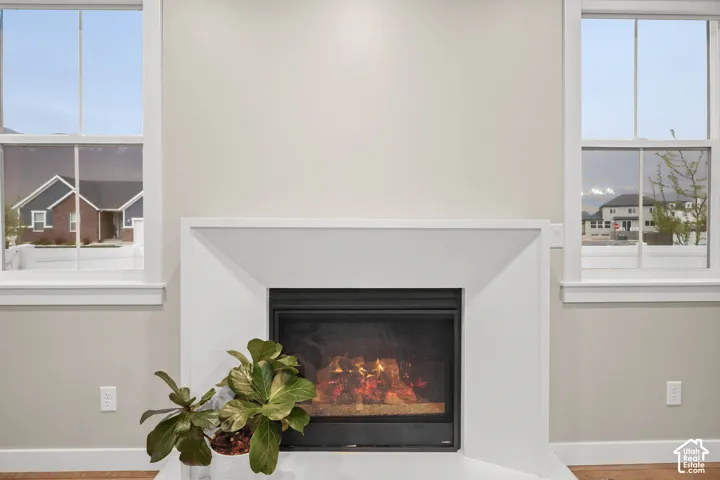 Fireplace featuring a minimalist white surround and a black metal firebox, flanked by two double-hung windows