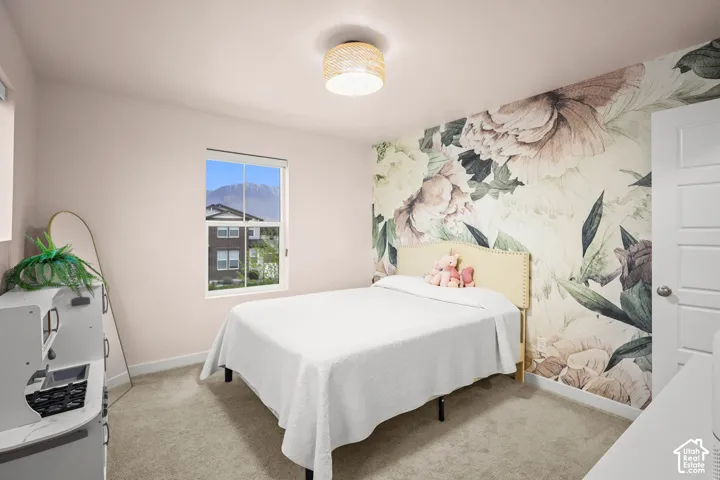 Bedroom featuring floral patterned accent wallpaper, neutral carpeting, a dual-pane window, and a woven-textured drum light fixture