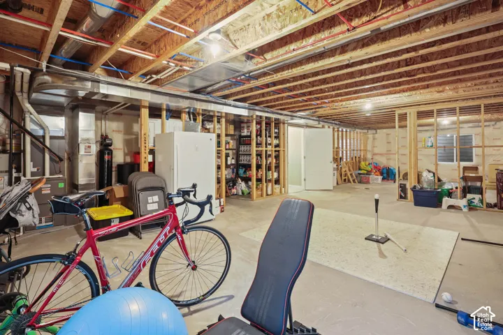 Unfinished lower level featuring exposed wood joist ceilings, concrete flooring, and an egress window