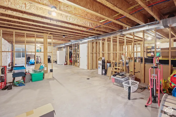Unfinished lower level featuring exposed wood framing, concrete flooring, exposed ceiling joists, and a single egress window