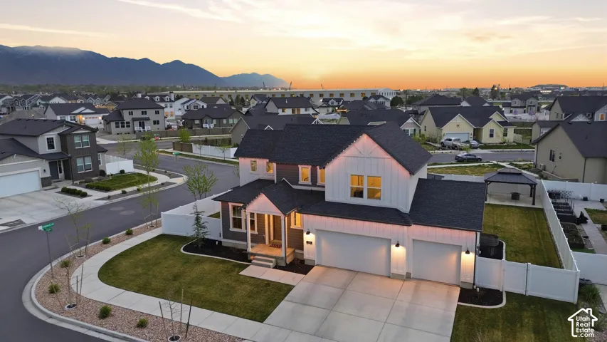 Two-story residence featuring a mixed-material exterior of vertical siding and lap siding, asphalt shingle roofing, a three-car garage, and a fenced backyard with a detached gazebo