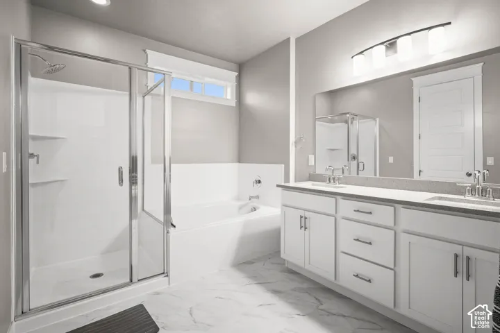 Bathroom featuring a dual-sink vanity with light-toned solid surface countertops, a walk-in shower with a glass enclosure, a separate soaking tub, and large-format tile flooring