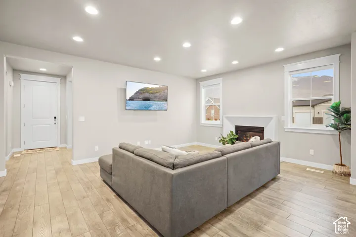 Living area featuring wood-finish flooring, recessed lighting, a fireplace with a minimalist surround, and double-hung windows