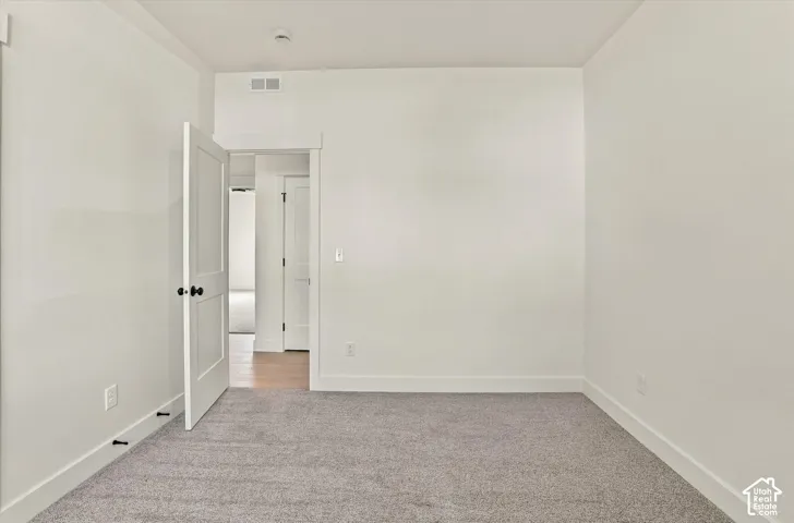 Neutral wall paint, high-pile carpet flooring, and a solid-core interior door with matte black hardware