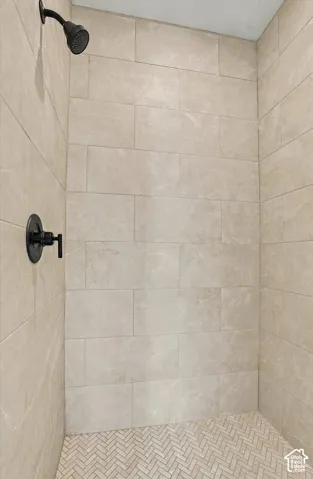 Walk-in shower featuring large-format rectangular wall tile, herringbone-patterned floor tile, and matte black plumbing fixtures