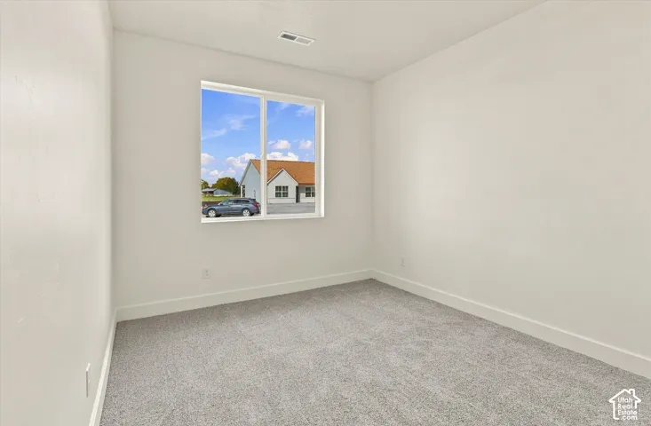 Neutral-toned interior room featuring grey carpeting, crisp white walls, and a large sliding window