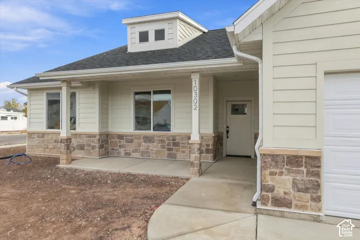 Exterior facade featuring horizontal siding, stone veneer base, covered front porch, dormer window, and shingle roof