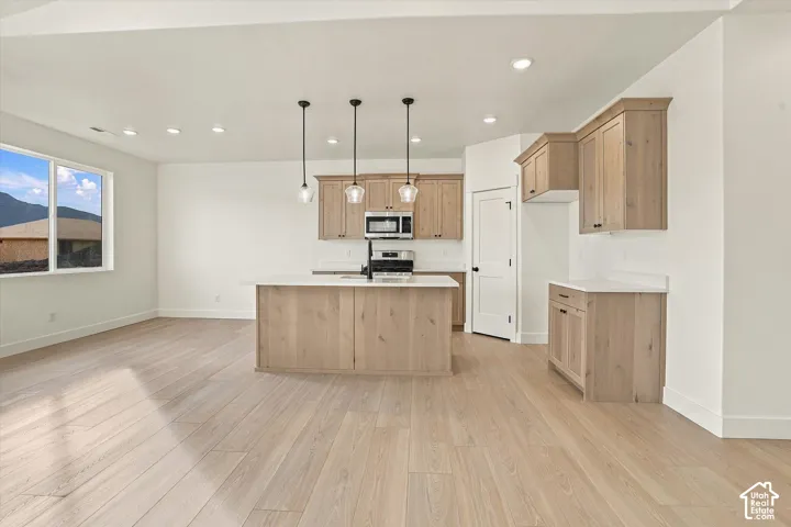 Kitchen featuring light wood-finish cabinetry, a central island with white countertops, recessed lighting, and wood-finish flooring