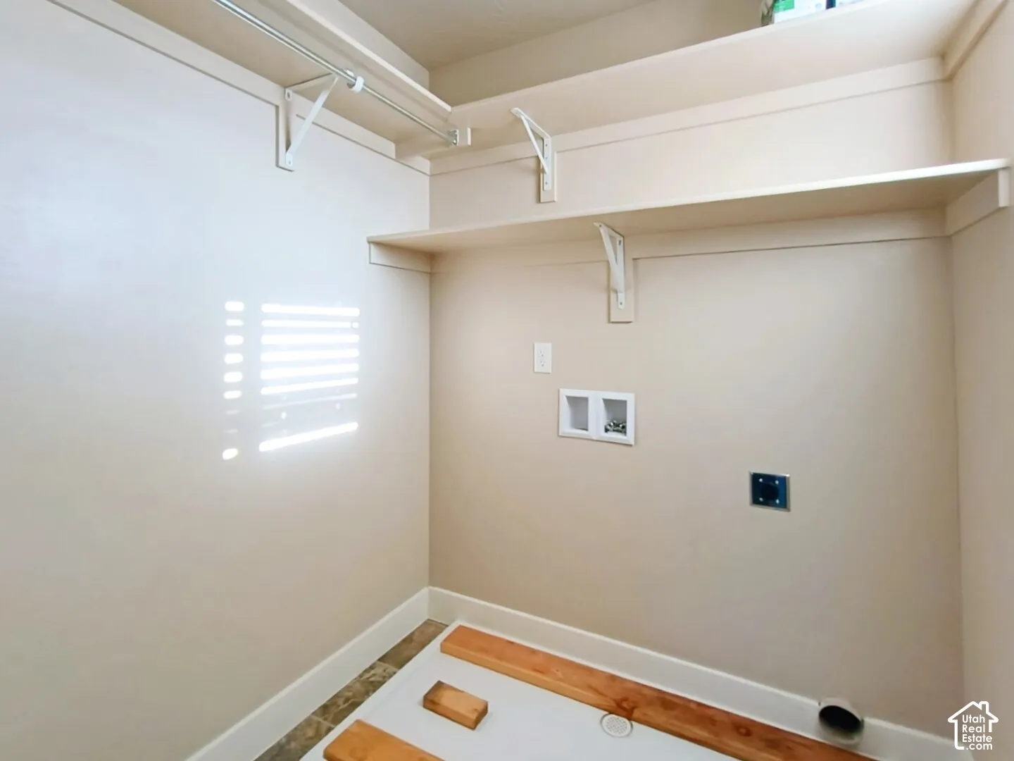 Utility area featuring custom shelving, a metal clothes rod, and dedicated washer and dryer hookups