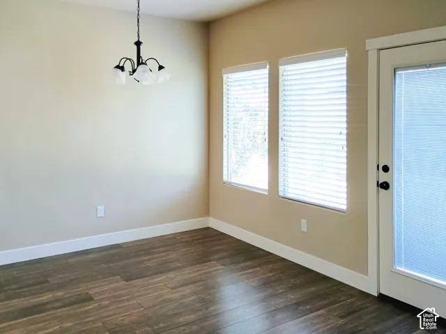 Wood-finish flooring, dual windows with horizontal blinds, black metal chandelier, and a glass-paneled exterior door