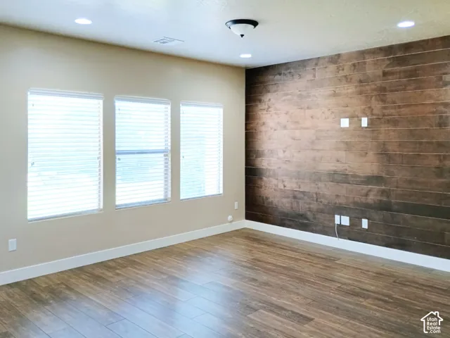 Wood-finish flooring, horizontal wood-plank accent wall, recessed lighting, and large windows with horizontal blinds