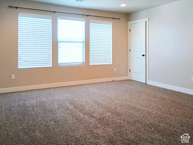 Interior room featuring wall-to-wall carpeting, three windows with horizontal blinds, a single-panel interior door, and recessed lighting