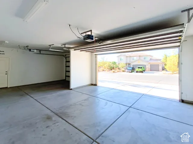 Multi-car garage featuring a concrete floor, automated overhead door system, and a dedicated service entry door