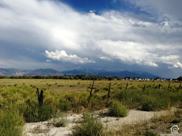 Expansive acreage featuring natural vegetation, wire fencing, and prominent mountain backdrops